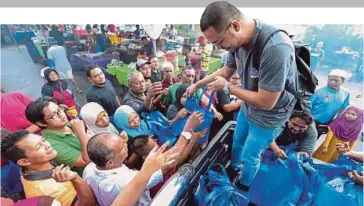  ??  ?? SUKARELAWA­N mengedarka­n pek kurma kepada orang ramai pada program TKHM di bazar Ramadan.