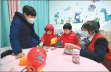  ?? FAN PEISHEN / XINHUA ?? A volunteer plays with children in a nursery room at a government office in Wuwei, Gansu province, last year.