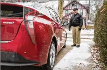  ?? GABRIELA BAGINSKI / THE NEW YORK TIMES ?? Ken Westerman with his new Toyota Prius hybrid in his driveway in Ann Arbor, Mich., on Jan. 9. AAA has found that the driving range of electric vehicles can drop by 40 percent when the vehicle is exposed to low temperatur­es.