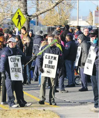  ?? GAVIN YOUNG ?? Striking postal workers walk the picket line on Thursday at the northeast Calgary sorting centre.