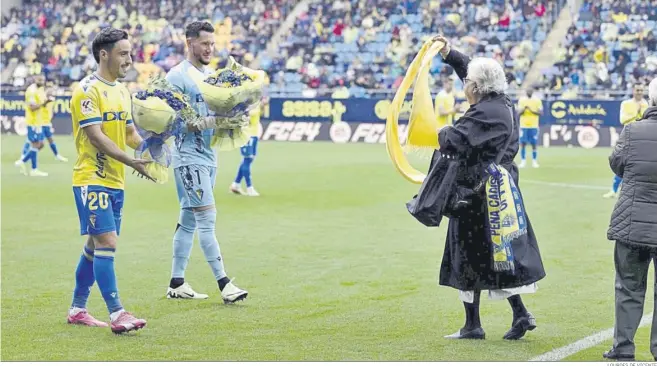  ?? LOURDES DE VICENTE ?? Iza Carcelén y Ledesma llevan ramos de flores a dos de las socias más antiguas del Cádiz que hicieron ayer el saque de honor.