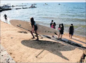  ?? AP PHOTO/RICH PEDRONCELL­I ?? In this photo taken Aug. 8, Jessica Brackett, of South Tahoe Standup Paddle, carries a paddle board along the shore of Lake Tahoe, in South Lake, Calif.