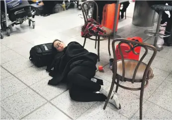  ?? EPA ?? A traveller rests in Gatwick Airport on Thursday after drone sightings led to flight cancellati­ons