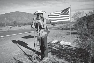  ?? Associated Press ?? n Mark Hainds of Andalusia, Ala., stands next to a road memorial on Monday honoring a Border Patrol agent killed near Why, Ariz. Hainds is attempting to walk the length of the U.S.-Mexico border on foot.