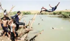  ?? —AFP ?? AL-KHAZIR: Iraqis staying at the Al-Khazir camp swim in a river near the camp for internally displaced people, located between Arbil and Mosul.