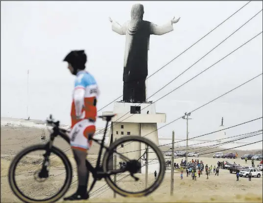  ?? Martin Mejia The Associated Press ?? A man rests with his bicycle Saturday near the Christ of the Pacific statue in Lima, Peru, which caught fire days before Pope Francis is scheduled to arrive in the South American nation.