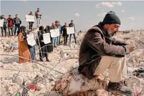  ?? Emily Garthwaite/New York Times ?? People protest the lack of aid amidst rubble from the earthquake in Syria. The U.S. has temporaril­y eased sanctions to allow humanitari­an aid to flow freely.