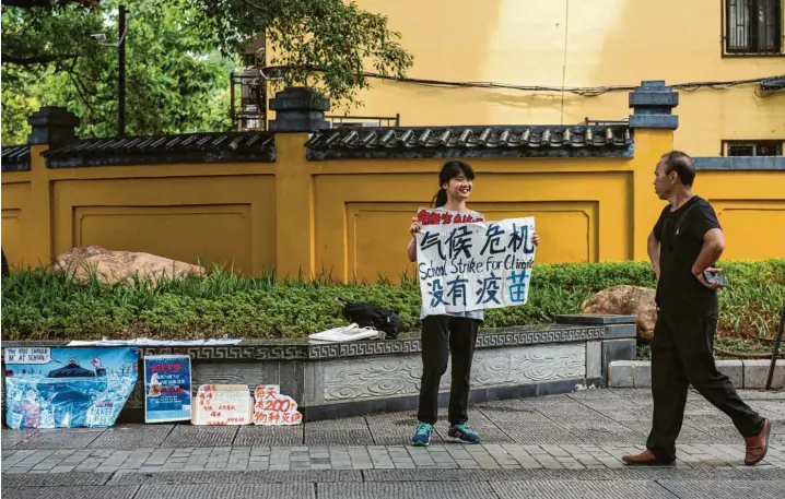  ?? Foto: Nicolas Asfouri/afp, Getty Images ?? Einer schaut dann doch – wenn auch wenig begeistert: Klima‰Aktivistin Ou Hongyi im Einsatz in ihrer Heimatstad­t Guilin.
