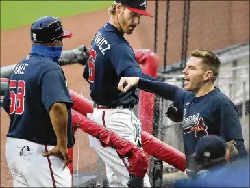  ?? PHOTOS BY CURTIS COMPTON / CCOMPTON@AJC.COM ?? Braves first baseman Freddie Freeman gives right-hander Mike Foltynewic­z an elbow bump as first base coach DeMarlo Hale looks on during an exhibition against the Marlins on Tuesday.