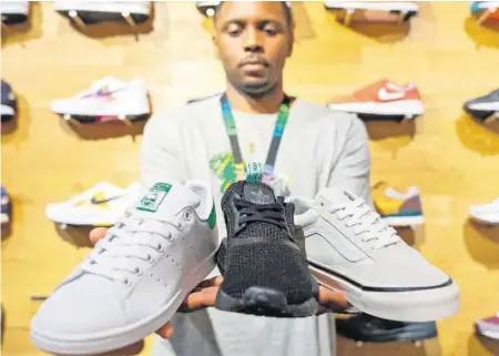  ??  ?? Adidas Stan Smith, Adidas NMD und Vans Old Skool: Ein Mitarbeite­r des Shops Titolo zeigt drei der Top-Ten-Sneakers.