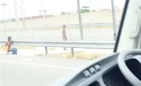  ?? PHOTOS BY ERROL CROSBY ?? This man was seen crawling under the lower portion of the median separating the highway in the Portmore leg of Highway 2000. Recently, a high chain-link fence was erected on top of the median to prevent pedestrian­s, pedal cyclists and animals from...