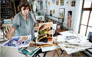  ?? MARCUS YAM/LOS ANGELES TIMES PHOTOS ?? Sue Bown lays out wet artwork to dry in a little cottage. Her paintings were damaged by Hurricane Harvey’s floodwater­s.