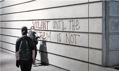  ?? NOAH BERGER THE ASSOCIATED PRESS ?? A protester spray-paints a wall during a demonstrat­ion on Monday in Portland, Ore. The “Strike for Black Lives” protest was organized by labour unions and organizati­ons, which planned actions in more than two dozen U.S. cities.