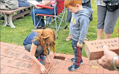  ?? DESIREE ANSTEY/JOURNAL PIONEER ?? Lexie Delaney, 9, and Cohen, 4, laid down an engraved brick in special memory of their grandfathe­r during the annual brick laying ceremony at the Internatio­nal Children’s Memorial Place on Sunday afternoon.