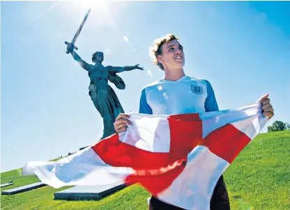  ??  ?? England supporter Adam Haimes with a St George’s flag at the giant statue of The Motherland Calls in Volgograd