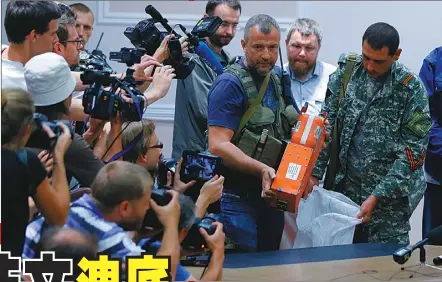  ??  ?? 烏克蘭叛軍將尋獲的馬­航MH17客機的兩具­飛安紀錄器(黑盒子)交給馬來西亞代表。 (歐新社)