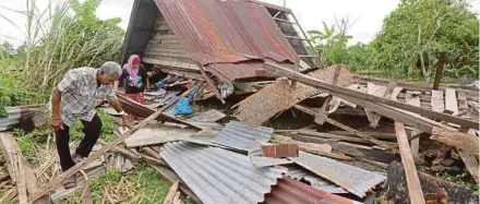  ?? (Foto Shahrizal Md Noor/bh) ?? Ahmad dan Rohani cuba mencari barang yang boleh diselamatk­an di bawah runtuhan rumah mereka di Kampung Sempering, Santan, Kangar.