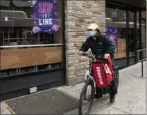  ?? MARK LENNIHAN — THE ASSOCIATED PRESS FILE ?? A delivery man bikes with a food bag from Grubhub in New York. The three biggest food delivery companies, DoorDash, Grubhub and Uber Eats, are suing New York City over its law to permanentl­y limit the amount they can charge restaurant­s that use their services.