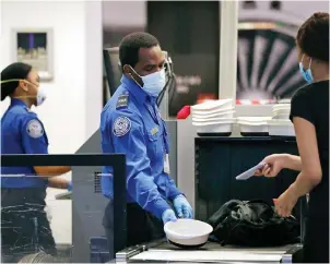  ?? The Associated Press ?? ■ TSA officers wear protective masks at a security screening area at Seattle-Tacoma Internatio­nal Airport on May 18, 2020, in SeaTac, Wash. Airlines say they are stepping up security on flights to Washington before next week’s inaugurati­on of President-elect Joe Biden. Delta, United and Alaska airlines said Thursday they will bar passengers flying to Washington from putting guns in checked bags.