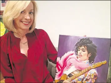  ?? STAPLES / GSTAPLES@AJC.COM GRACIE BONDS ?? Lucy Fugate of Vinings shows off a colorful portrait of the late artist Prince by one of Georgia’s prison inmates. The painting will be among some 200 pieces of inmate art on display and up for sale Feb. 13-16. Proceeds will benefit HeartBound Ministries, a nonprofit organizati­on supporting Georgia’s correction­al staff and inmates.