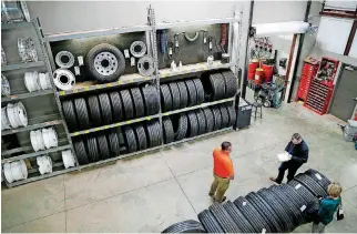  ??  ?? ABOVE: Dan West, in orange, gives a tour of a tire repair center at one of the Guthrie Love’s Travel Stops locations.