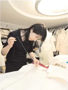  ?? Courtesy of Lee Kyoung-jae ?? Lee Kyoung-jae, CEO of Sewing for the Soil, works on a wedding garment Seongbuk-dong, Seoul. in her office in