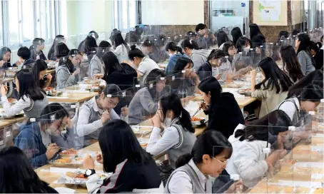  ?? AFP ?? S. Korea SchoolS begin: Students sit behind protective screens as a preventati­ve measure against coronaviru­s as they eat lunch at a high school in Daejeon on Wednesday. South Korean students returned to school on May 20 after a virus delay of more than two months. —