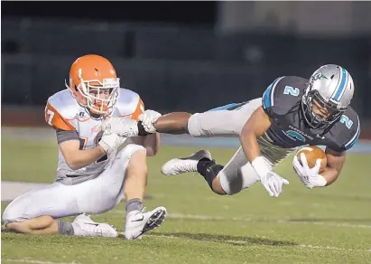  ?? ROBERTO E. ROSALES/JOURNAL ?? Artesia High’s Ty Johnson, left, grasps at the foot of Cleveland High’s elusive running back Dorian Lewis in the second quarter of Friday night’s game at Cleveland High School in Rio Rancho.