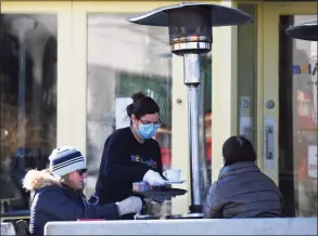  ?? Tyler Sizemore / Hearst Connecticu­t Media ?? Darien residents Holly Galper, left, and Jane Glassmeyer are served hot beverages by Marjorie Yavar as they sit next to heaters in the outdoor seating area at Meli-Melo on a cold day in Greenwich in November.