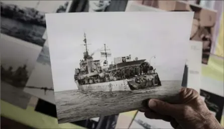  ?? DARREN CALABRESE, THE CANADIAN PRESS ?? George Borgal holds an archival photo of HMCS Saguenay in his home in Halifax. HMCS Saguenay was hit by a torpedo in December 1940, but still managed to steam almost 450 kilometres, backwards, to port at Barrow-in-Furness, England. Borgal’s father was...