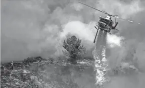  ?? CINDY YAMANAKA/THE ORANGE COUNTY REGISTER VIA AP ?? A firefighter watches an aerial drop in Murrieta, Calif., on Sunday. Several area homes appeared to have been evacuated.