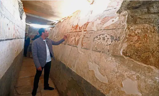  ?? — Reuters ?? Important discovery: A guide from the Antiquitie­s Ministry inspecting the tomb of a priestess named ‘Hetpet’ at the Giza plateau, the site of the three ancient pyramids on the outskirts of Cairo, Egypt.