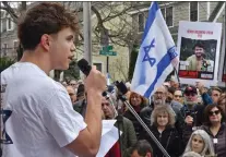  ?? CHRIS CHRISTO — BOSTON HERALD ?? Ben Spira talks about his friend Hersh Goldberg-Polin (seen on a poster at right) during the gathering to rebuild the vandalized hostage memorial wall in front of a home on Homer Street in Newton Sunday.