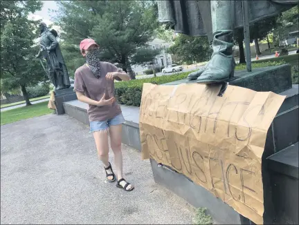  ?? TANIA BARRICKLO — DAILY FREEMAN ?? Frances Cathryn attaches a homemade sign reading ‘Whose Rights’ and ‘Whose Justice’ to the base of the George Clinton statue at Academy Green Park in Kingston, N.Y., on Wednesday, July 15.