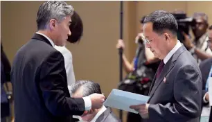 ?? AP ?? North Korean Foreign Minister Ri Yong Ho receives an envelope from US Ambassador to the Philippine­s Sung Kim before the start of the 51st Asean Foreign Ministers Meeting in Singapore. —