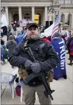  ??  ?? A man carries a rifle during a rally in support of President Donald Trump at the state capitol in Lansing on Wednesday.