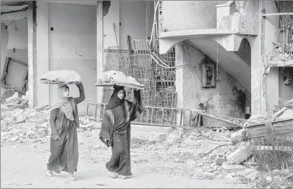  ?? ?? Se calcula que, por las hostilidad­es, a diario 37 madres pierden la vida. En la imagen, en Rafah, dos mujeres llevan pan para sus familias entre los escombros. Foto Afp