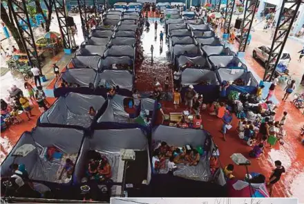  ?? AGENCY PIX ?? Evacuees sitting in tents at a relief centre in Marikina City, east of Manila, yesterday. (Inset) Villagers looking at what is left of their home in Cagayan province.