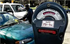  ?? DAVID I. ANDERSEN / THE (CLEVELAND) PLAIN DEALER ?? A parking officer with the city of Cleveland gives out a parking ticket to a car in 2001. Thousands of people who had been ticketed for parking illegally in Cleveland as long ago as 2000 recently received notices from the attorney general’s office, which the city has contracted to collect on unpaid parking debts.