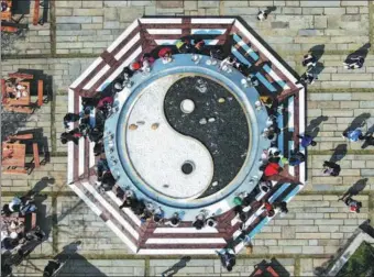  ?? YANG BO / CHINA NEWS SERVICE ?? Visitors to Maoshan, a sacred Taoist site in Jiangsu province, eat local delicacies around a 10-meter-wide pot decorated as the symbol for yin and yang on Saturday. The scenic spot holds a food festival around this time every year.