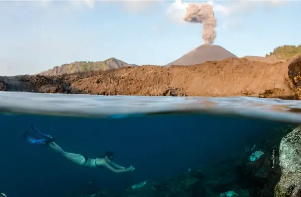  ??  ?? A plume of ash and smoke rising in the distance while a swimmer enjoys the underwater sights of Barren