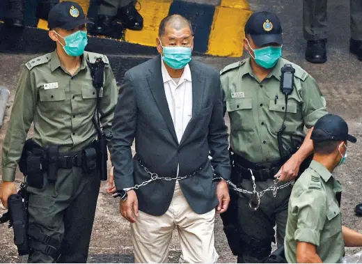  ??  ?? CRACKDOWN: Pro-democracy businessma­n Jimmy Lai, chained round his waist and wrists to a guard, is marched to court yesterday