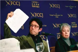  ?? — AFP ?? TOKYO: Nuclear researcher Hidetake Ishimaru (L) shows documents as Noriko Matsumoto, who left her house in Fukushima prefecture after the 2011 nuclear disaster, looks on during a press conference.