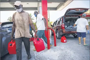  ?? TIM AYLEN-ASSOCIATED PRESS ?? A resident walks with containers filled with gasoline at Cooper’s gas station before the arrival of Hurricane Isaias in Freeport, Grand Bahama, Bahamas, Friday.