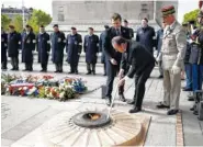  ?? THE ASSOCIATED PRESS ?? French President-elect Emmanuel Macron, center behind, watches outgoing President Francois Hollande lighting up the Tomb of the Unknown Soldier during a ceremony to mark the end of World War II at the Arc de Triomphe in Paris on Monday.