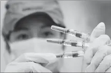  ?? CHEN XIAOGEN / FOR CHINA DAILY ?? A Sinovac technician displays CoronaVac vaccine samples at a factory in Beijing in July 2021.