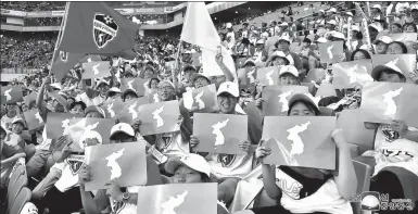  ?? KCNA VIA REUTERS ?? People hold posters of a unified Korea at the friendly soccer match between ROK and DPRK workers in Seoul on Saturday, in this photo released by the DPRK’s Korean Central News Agency on Monday.