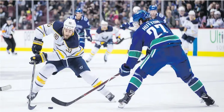  ??  ?? Buffalo Sabres centre Ryan O’Reilly skates with the puck while being watched by Vancouver Canucks defenceman Ben Hutton.