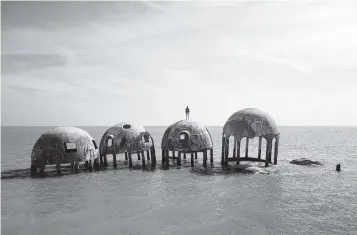  ?? ALEX MARKOW ?? British artist Simon Faithfull stands atop one of the almost-submerged structures of Dome House near Marco Island.