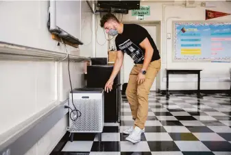  ?? Santiago Mejia / The Chronicle ?? Braden DeWitt adjusts the smart air purifier inside his classroom at McClymonds High School in Oakland. The district may require students and staff to be vaccinated.